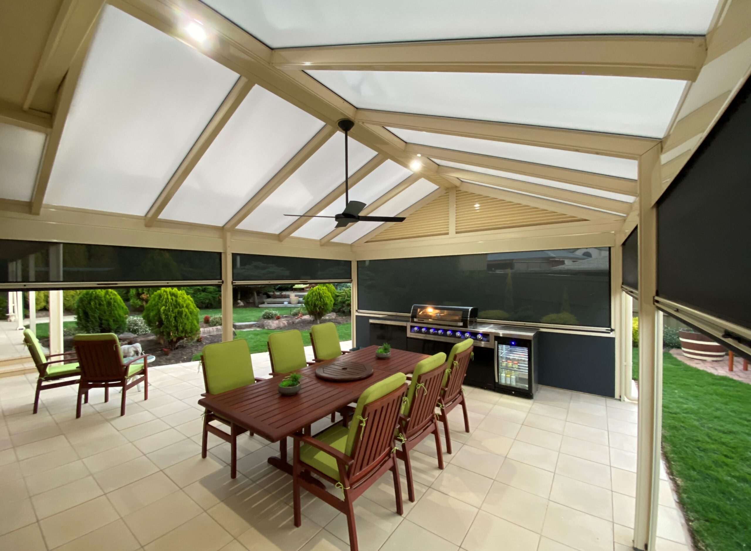 A stylish Colorbond verandah with a pitched roof design, featuring a combination of steel and fibreglass panels, providing a shaded outdoor space in a residential backyard. The verandah seamlessly integrates with the house, offering a comfortable and inviting patio area for relaxation and entertainment.