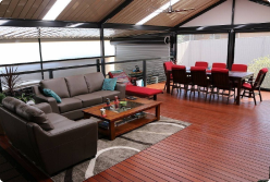 A cozy, enclosed verandah featuring a comfortable couch, with Colorbond roofing and Fibreglass panels, enhancing the outdoor space with stylish design elements.