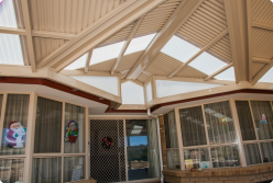 A modern Colorbond verandah with a sleek design, featuring a sturdy steel frame and Fibreglass roofing. The verandah extends over a spacious patio area, offering an attractive outdoor space for relaxation and entertainment. The structure is a stylish addition to the home, showcasing expert craftsmanship by professional builders.